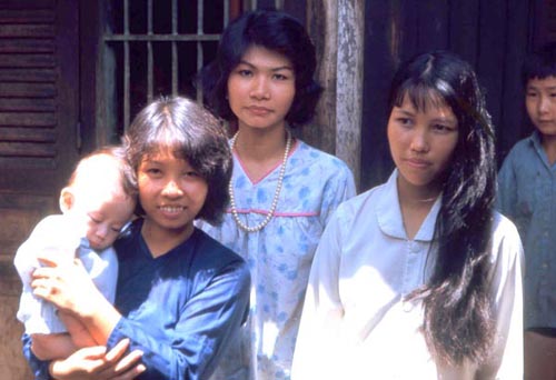Bien Thuy Air Base. Oldest sister raises youngs infant. Mamasan still at the river doing laundry. Young women helping at the Budhist Refugee Center. MSgt Summerfield, 1968: 13