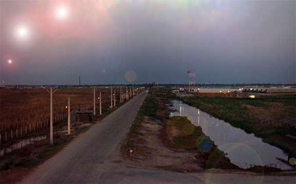65) Bình Thủy Air Base Perimeter: This is a  photo taken from approximately the same location as photo #65 above(see the SP Tower, center-horizon, just to right of the paved road). It is a dusk composite from the below photo (taken during broad daylight.<strong><br />
Photo by: Dennis Hutchings.</strong> Composite by: Don Poss.