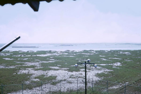 11. Cam Ranh Bay AB. Perimeter Tower view. M-16 (lower-left) and .50-Cal's barrel and floodlights overlook the perimeter. 1970.