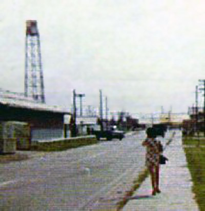 20. Cam Ranh Bay AB, Vientmaese civilian walking to work. Did you notice here dress-pattern matches the Water Tower is on the left? 1972-1973. Photo by: Steve Ray, LM 304, CRB, 483rd SPS; KRT, 388th SPS. 1972-1973.