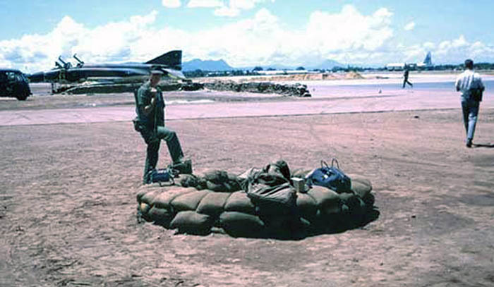 3. Đà Nẵng AB, 366th SPS. SP Post. No where to hide from a blistering sun. When the rains come, the fighting-hole will fill with water. Last of the old sandbag revetments visible for F-4 Phantom parking. Photo by: James Paul Mashburn 1966-1967.