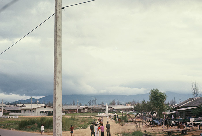 8. Đà Nẵng AB, Tent City: ARVN families come outside of living quarters to watch VNAF dive bomb rebel Buddhist downtown. 1965. Note the two small black dots that are VNAF dive bombers.