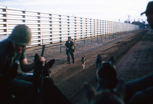 20. Đà Nẵng AB, K-9 Growl Pad: Airman walks to post from Guardmount, as K-9 handlers and dogs ride to perimeter posts. 1965.