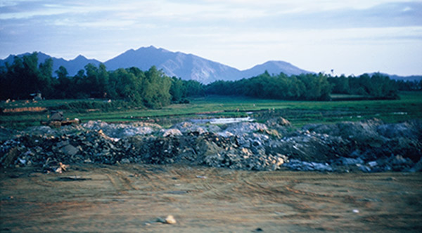 38. Đà Nẵng AB, K-9 Growl Pad: View from K-9 posting truck passing trash-dump area, N/B East-Perimeter road, ready to curve W/B at the airbase's North-Perimeter. 1965.