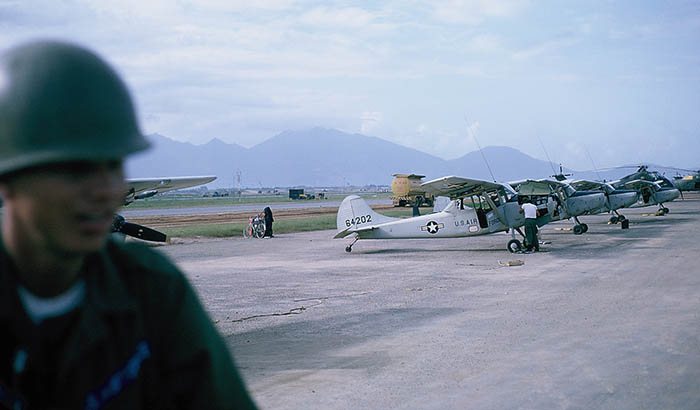37. Đà Nẵng AB, flight line: AP Truck posting on flight line pass by O-1E Bird Dogs parking. 1965.