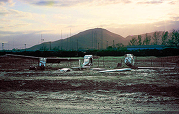41. Đà Nẵng AB, flight line: View of O-1E boneyard from west side of AP Tent City. Hill 327 in background. 1965.
