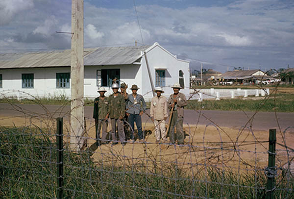18. Đà Nẵng AB, Tent City: Vietnam, land of cement-telephone poles and wooden sidewalks. Vietnamese electricians working on the power lines. 1965.