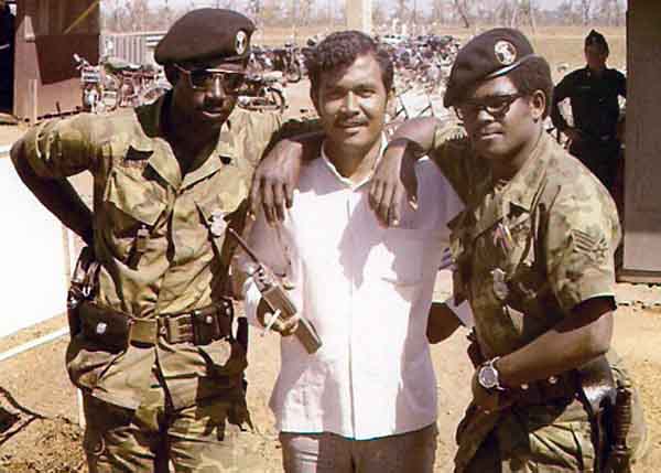 2b. NKP Main Gate: Close Up: Sgts Davenport and Clement, with the LE interpreter, Mr. Daisha (An Indonesian). Photo by: Roderick K. Duncan.