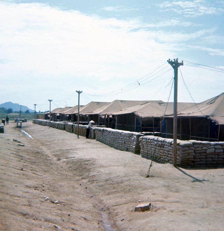 28. Phan Rang Air Base: US Army area, with Rows of Tent-Huts walled-in with sandbags. Soldier, center-far-left: HEYYYYYY... DINKY-DAO -- Quit Stealin' them sandbags!