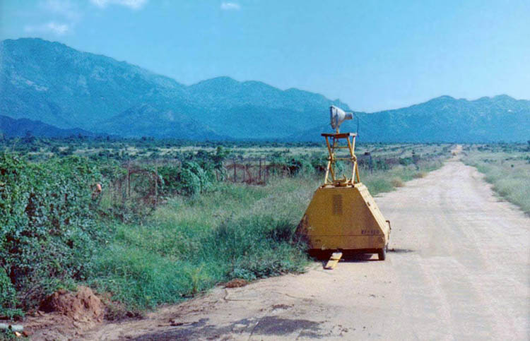 16. Phan Rang AB: Bomb Dump Preimeter Road. Auxiliar powered Flood Lights light fields beyond wire along the perimeter road.