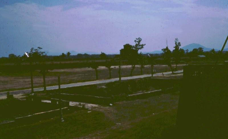 27. This is the view from our back tower looking to the west. We were stationed near the coast and the area was mostly water. You can see the fence line just below the tower. The lights on the poles came on at night so we were pretty well lite up at night. We also had claymore mines, trip flares and ground sensors along the fence line. [click photo to see original view]