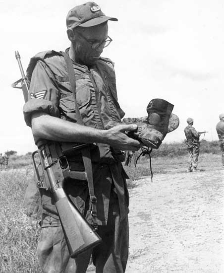 14. NCO examines VC boots, discarded while fleeing. 600th Photo Squadron, Vietnam.