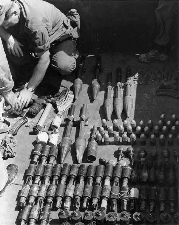 15. Photo right: SPSs check out VC/NVA weapons cache displayed. 600th Photo Squadron, Vietnam.