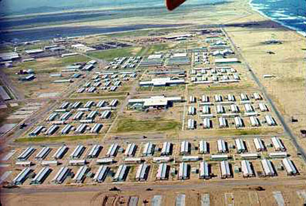7) An aerial of the base taken from an HH-43 Pedro helicopter. It is at the
south end of the base along the shoreline looking towards the north. If my
memory serves me, the metal hooches at the bottom of the picture were the
31st SPS barracks area. The small buildings between the hooches are bomb
shelters. The flight line area is in the upper left edge of the picture.