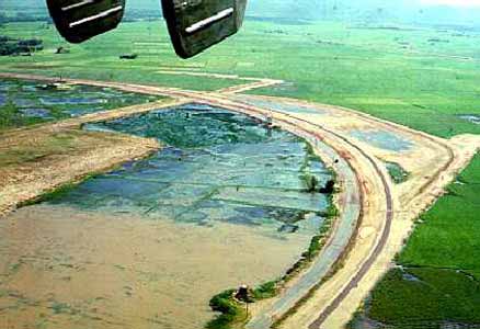 9) The same HH-43 Pedro mission and shows an area of the perimeter
on the northwest side of the base near the end of the runways. Note the
three towers situated along the perimeter road.